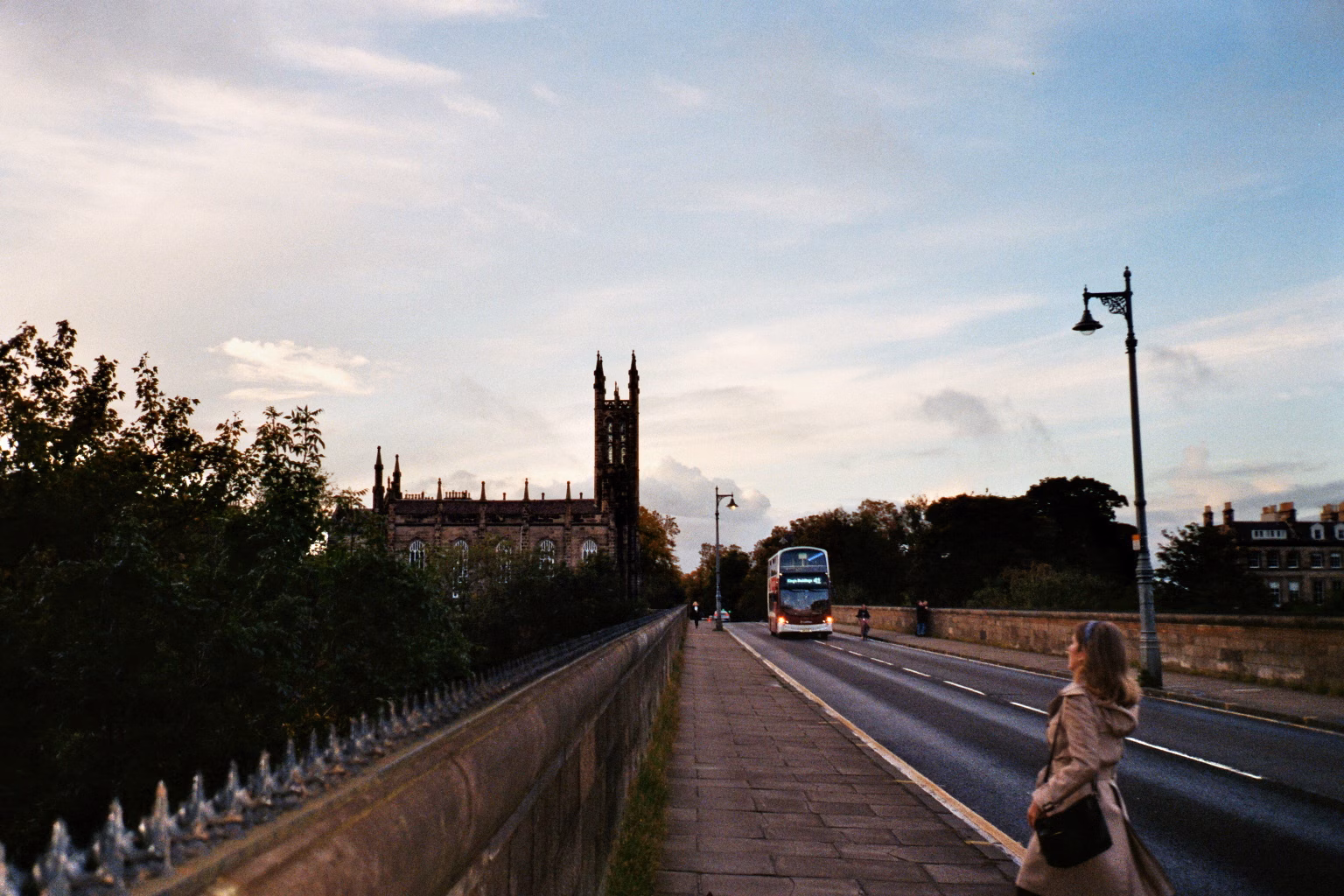 Abendliche Straße in Edinburgh mit Blick auf eine gotische Kirche und einen Doppeldeckerbus.