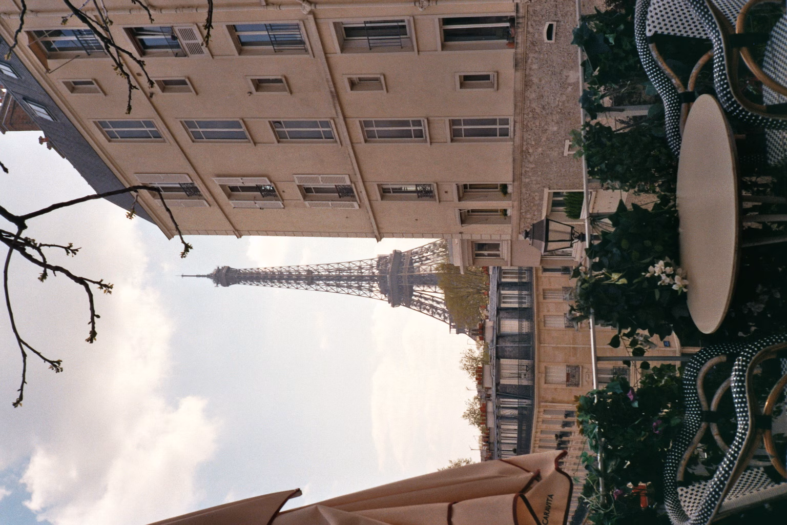 Analogfoto von einem Pariser Balkon mit Blick auf den Eiffelturm hinter klassischen Wohngebäuden. Warmer Vintage-Look.
