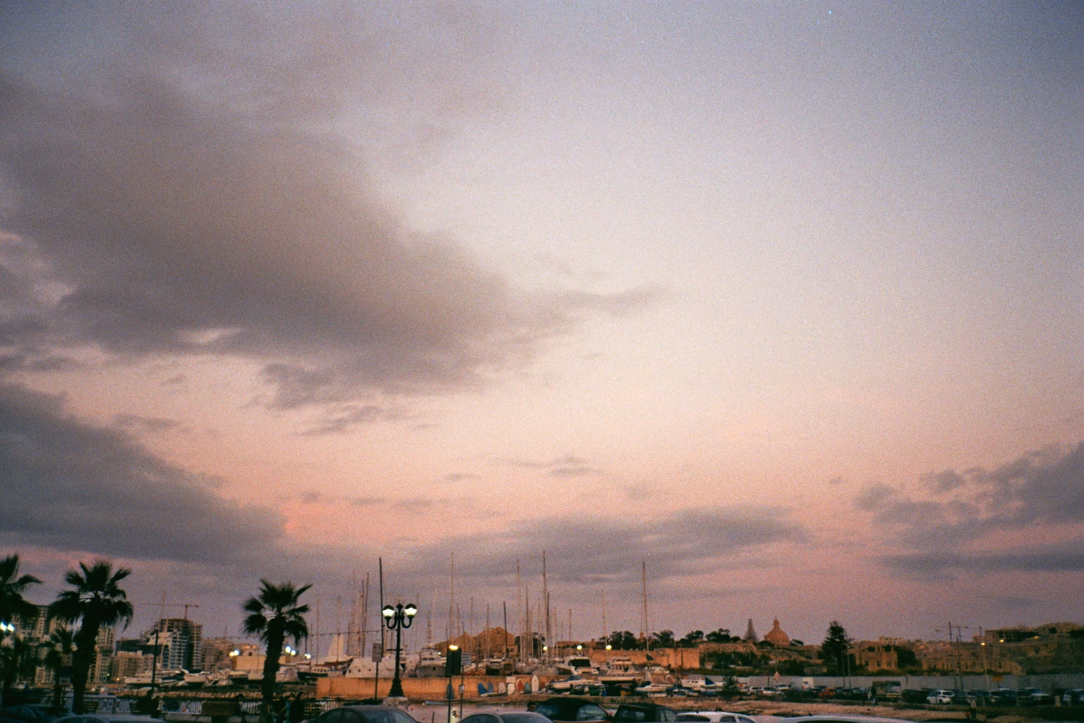 Ein maltesischer Yachthafen mit zahlreichen Booten unter einem rosa-violetten Abendhimmel.